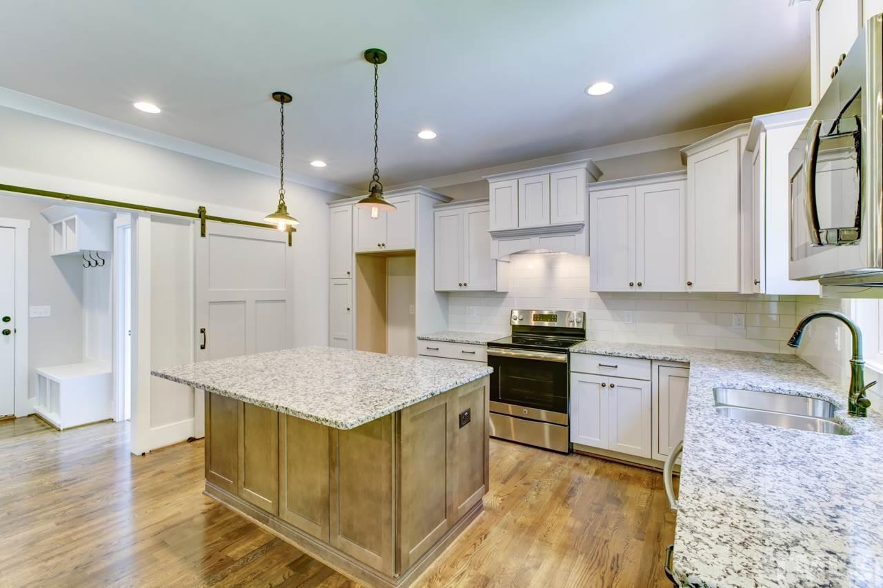 1033 Sky Wave Trail, Unit 8 Raleigh, NC 27603 - Photo 6 of 23 a kitchen with stainless steel appliances granite countertop a stove a sink a refrigerator and white cabinets with wooden floor