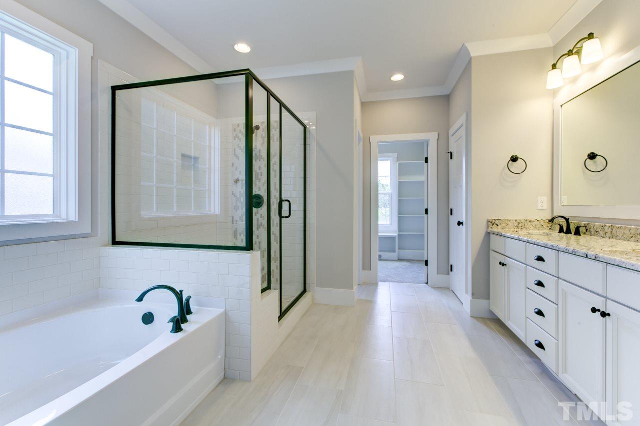 1033 Sky Wave Trail, Unit 8 Raleigh, NC 27603 - Photo 9 of 23 a bathroom with a granite countertop sink a mirror a bathtub and shower