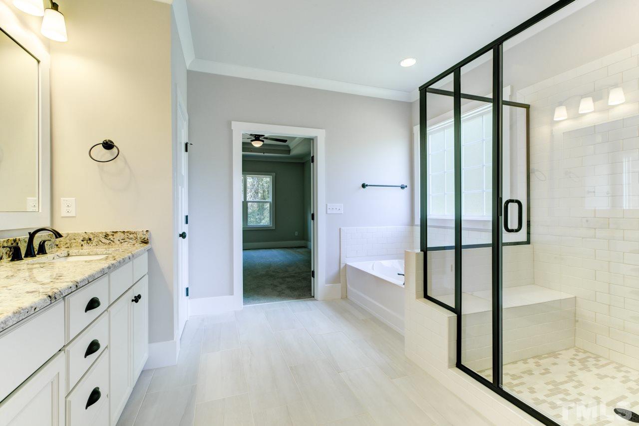 1033 Sky Wave Trail, Unit 8 Raleigh, NC 27603 - Photo 10 of 23 a spacious bathroom with a granite countertop sink a mirror and shower