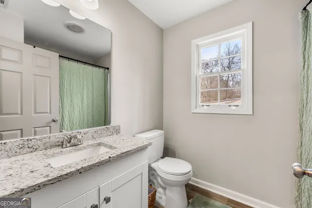 a bathroom with a granite countertop sink a toilet and a mirror