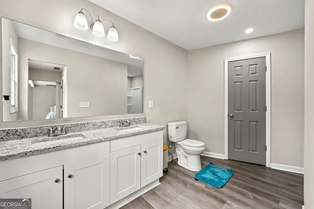 a bathroom with a granite countertop sink a toilet and a mirror