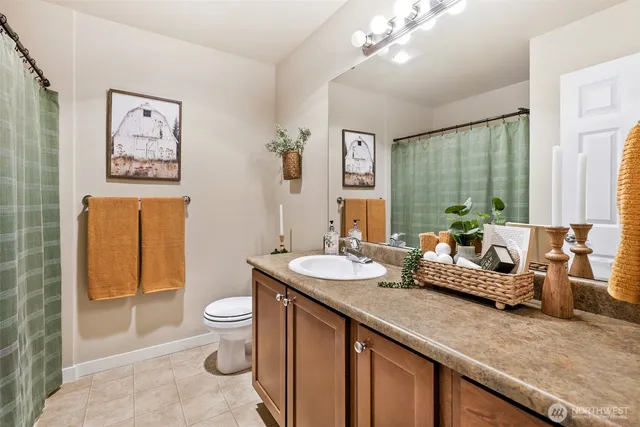 a spacious bathroom with a granite countertop sink a toilet a mirror and shower