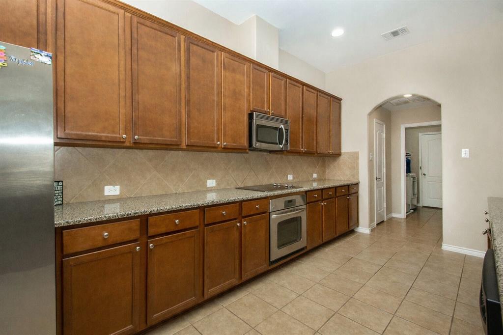 9754 Boyton Canyon Road Frisco, TX 75035 - Photo 12 of 21 a kitchen with stainless steel appliances granite countertop a stove a sink and a microwave