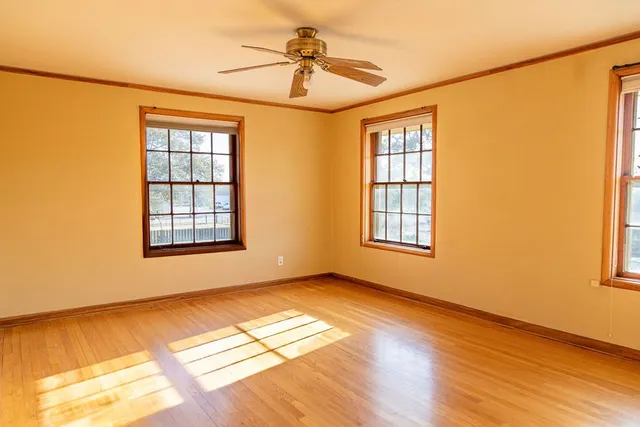 a view of an empty room with window and wooden floor