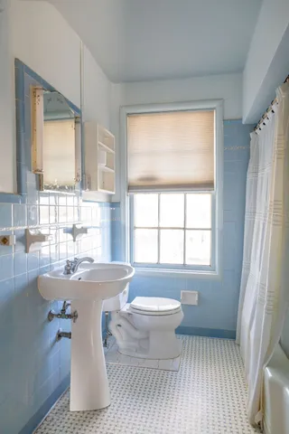 a bath room with a toilet tub and a window