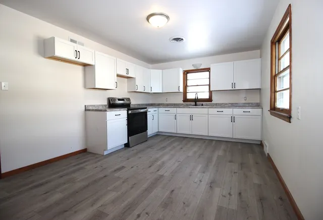 a kitchen with granite countertop a sink cabinets wooden floor and stainless steel appliances