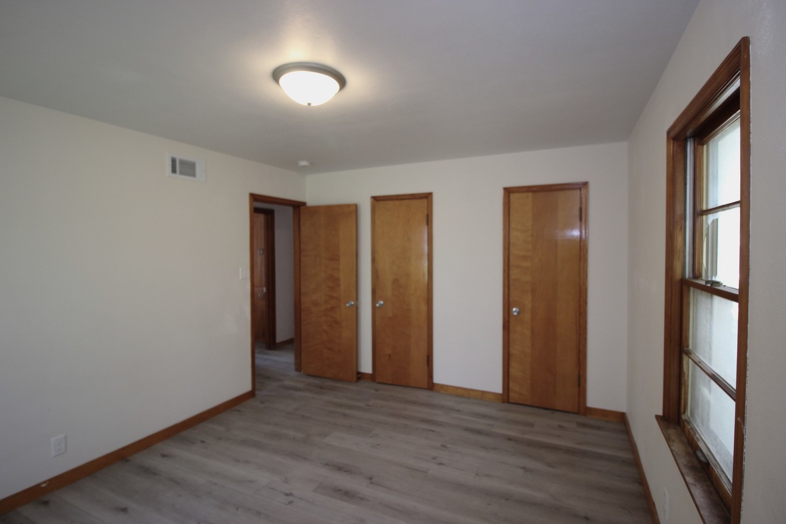 108 East Gridley Road Gridley, IL 61744 - Photo 10 of 22 a view of an empty room with wooden floor and a window