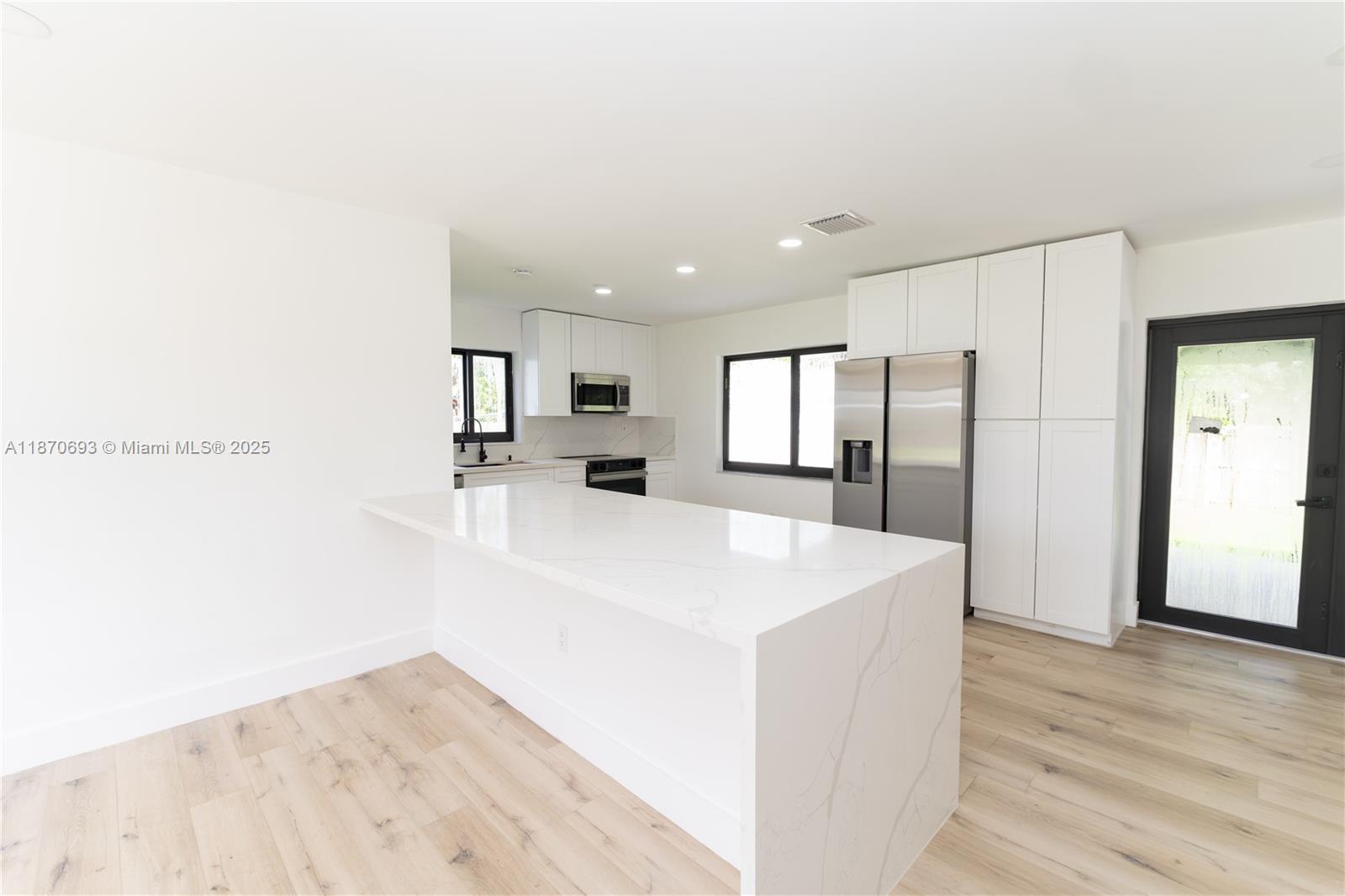 10441 Southwest 50th Terrace Miami, FL 33165 - Photo 6 of 19 a large white kitchen with wooden floor and a sink