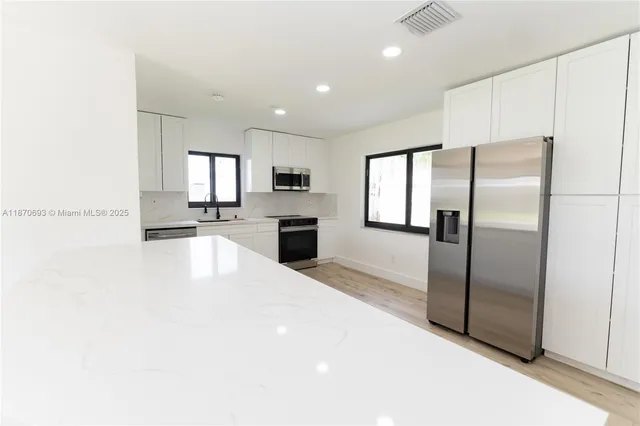 a large kitchen with a refrigerator a stove top oven a sink and dishwasher