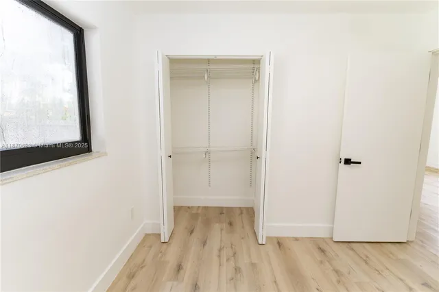 a view of a hallway with wooden floor and a bathroom