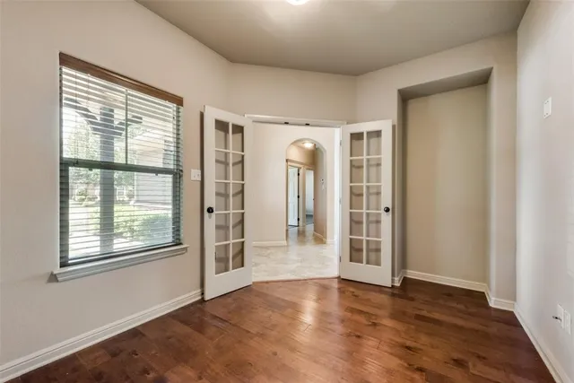 an empty room with wooden floor and windows