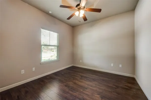 an empty room with wooden floor closet and windows