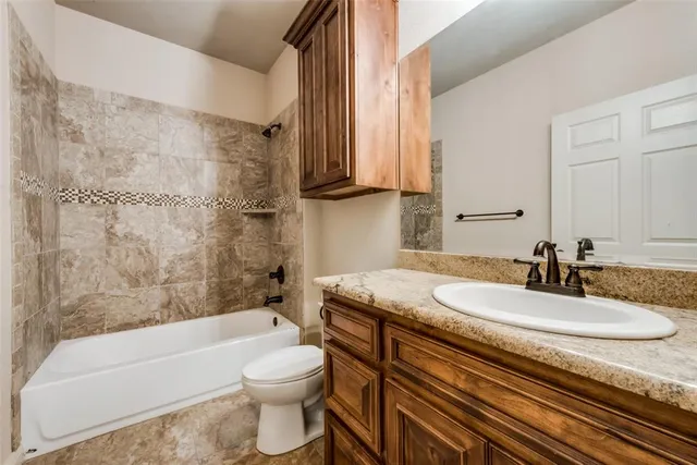 a bathroom with a granite countertop sink a toilet a mirror and bathtub