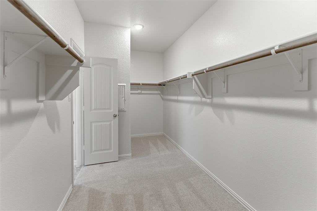 1329 Frio Drive Springtown, TX 76082 - Photo 19 of 25 Spacious walk-in closet featuring light gray carpeting, crisp white walls, extensive shelving, and multiple hanging rods for organization