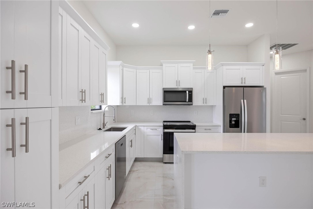 2909 37th Street Southwest Lehigh Acres, FL 33976 - Photo 14 of 29 a kitchen with stainless steel appliances a sink a stove a refrigerator cabinets and a window