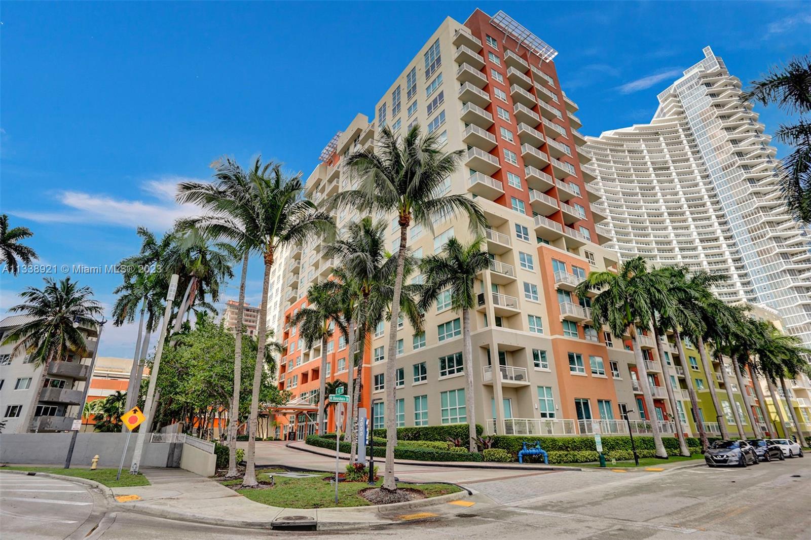 a front view of multi story residential apartment building with yard and sign board