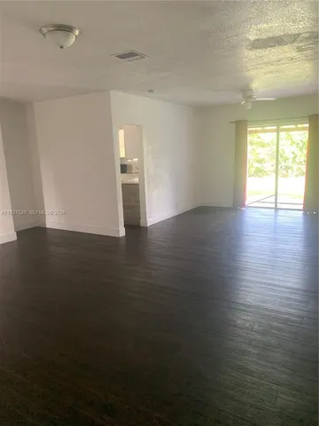 an empty room with wooden floor and windows with curtains