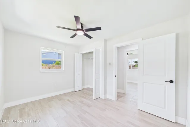a view of empty room with wooden floor and fan