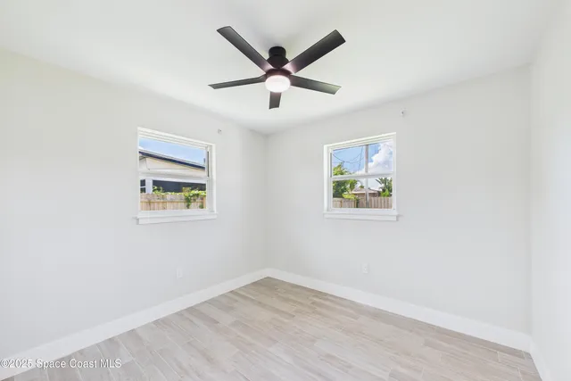 an empty room with wooden floor and ceiling fan