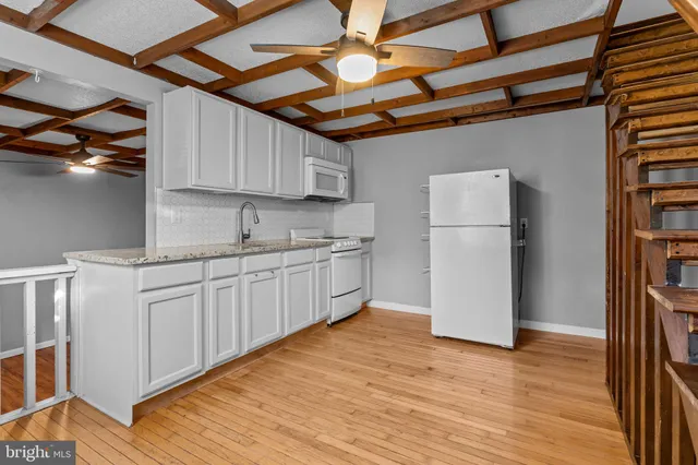 a kitchen with a refrigerator a stove cabinets and wooden floor