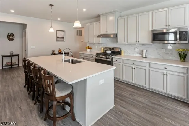 a kitchen with stainless steel appliances a stove a sink a microwave a refrigerator and cabinets