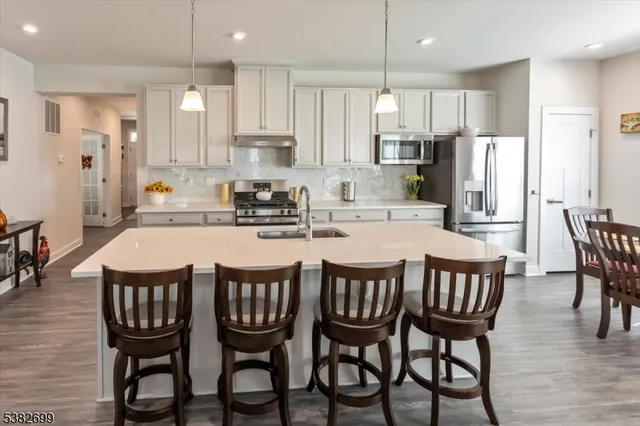 a kitchen with stainless steel appliances granite countertop a dining table and chairs