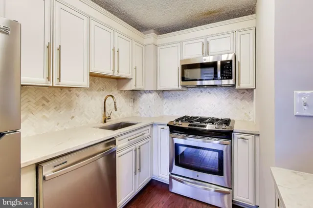 a kitchen with stainless steel appliances granite countertop white cabinets and a stove top oven