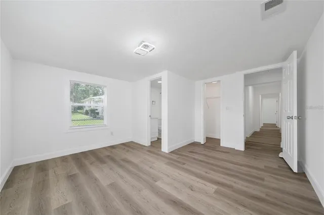 a view of an empty room with wooden floor and window