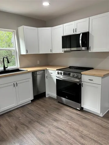 a kitchen with cabinets appliances and wooden floor