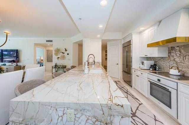 a large white room with kitchen island a stove a sink dishwasher with a dining table and chair