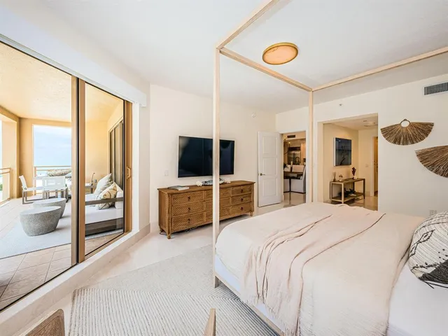 a bedroom with a bed a large window and flat screen television