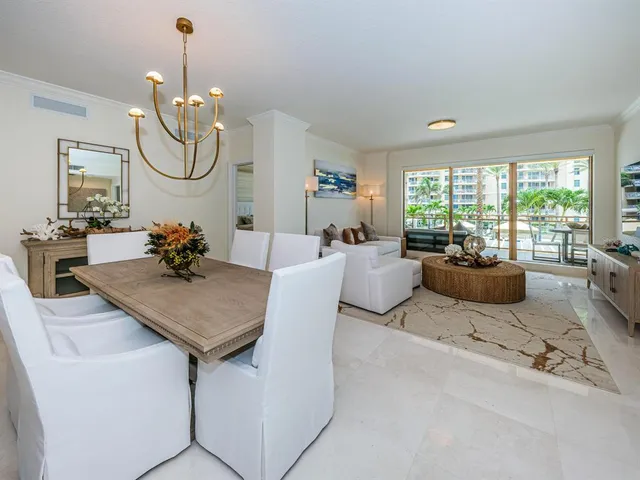 a living room with furniture a chandelier a dining table and a large window