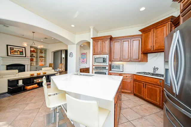 a kitchen with stainless steel appliances granite countertop a refrigerator a stove a sink a dining table and chairs with wooden floor