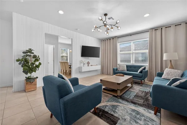 a living room with furniture a chandelier and a flat screen tv