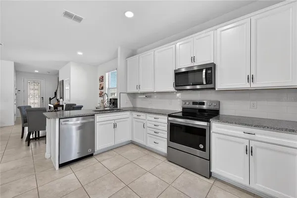 a kitchen with white cabinets granite counter tops and a stove top oven