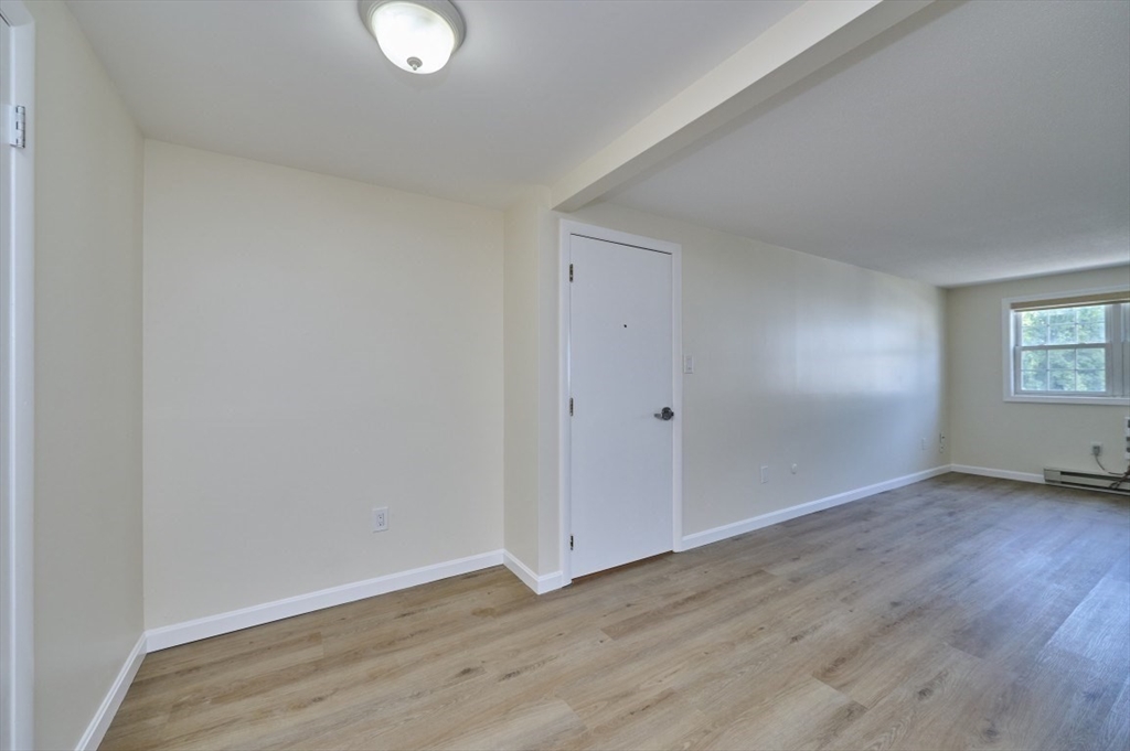 15 Old Colony Lane, Unit 7 Arlington, MA 02476 - Photo 6 of 12 a view of an empty room with wooden floor and a window