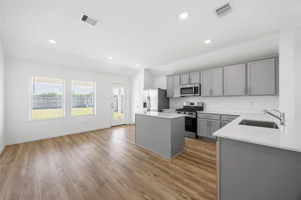 a kitchen with a sink wooden floor stainless steel appliances and cabinets
