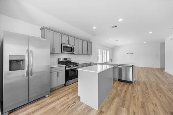 a large kitchen with a center island stainless steel appliances and cabinets
