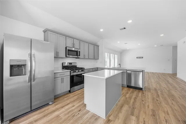 a large kitchen with a center island stainless steel appliances and cabinets