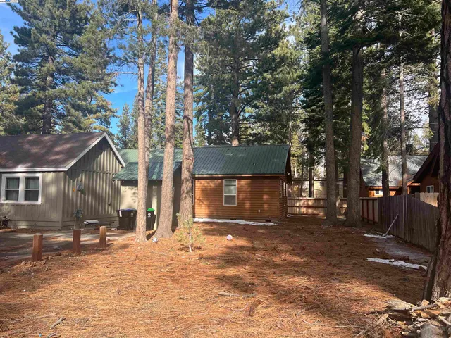 a backyard of a house with large trees and outdoor seating