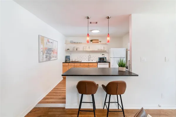 a kitchen with stainless steel appliances granite countertop a stove a refrigerator and a dining table with wooden floor