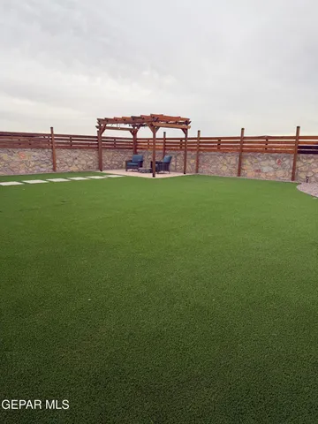 a view of a green field with house in the background