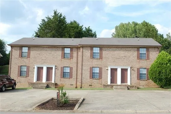 a front view of a house with trees and plants