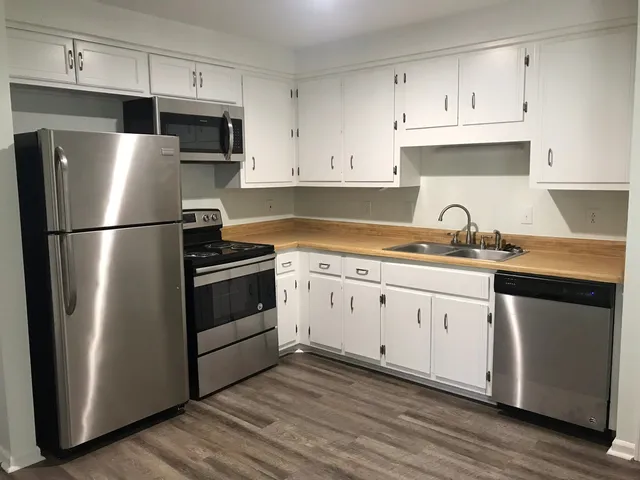 a kitchen with cabinets stainless steel appliances a sink and wooden floor