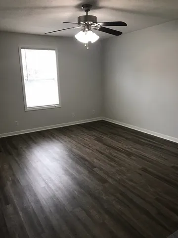 a view of room with window ceiling fan and hardwood floor