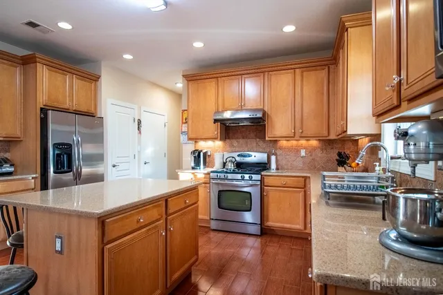 a kitchen with kitchen island granite countertop wooden cabinets and stainless steel appliances