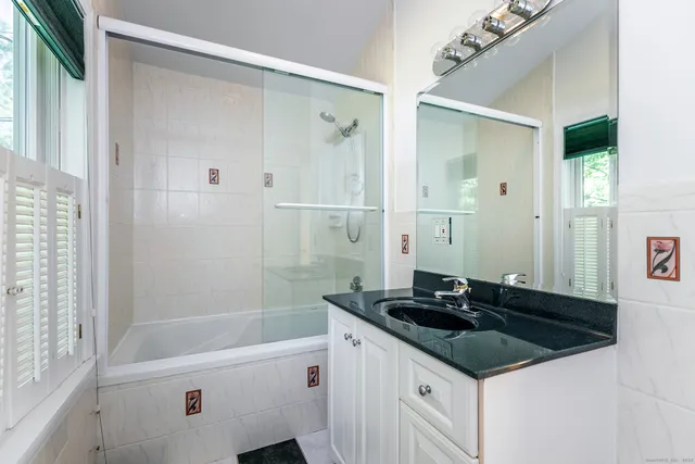 a bathroom with a granite countertop sink a shower and a mirror