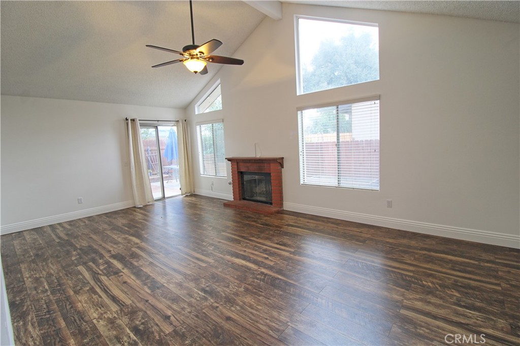 13597 Chaparral Trail Yucaipa, CA 92399 - Photo 3 of 12 an empty room with wooden floor chandelier fan and windows