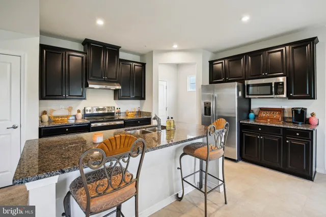 a kitchen with stainless steel appliances granite countertop a stove top oven a sink dishwasher a dining table and chairs with wooden cabinets