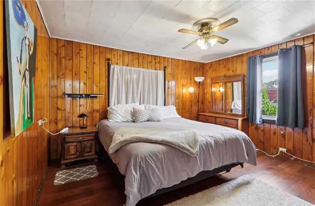 a bedroom with a bed a dresser and a large window